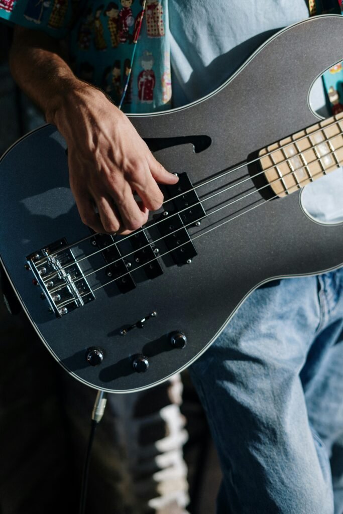 Musician performing with a sleek electric bass guitar in a home studio setting.